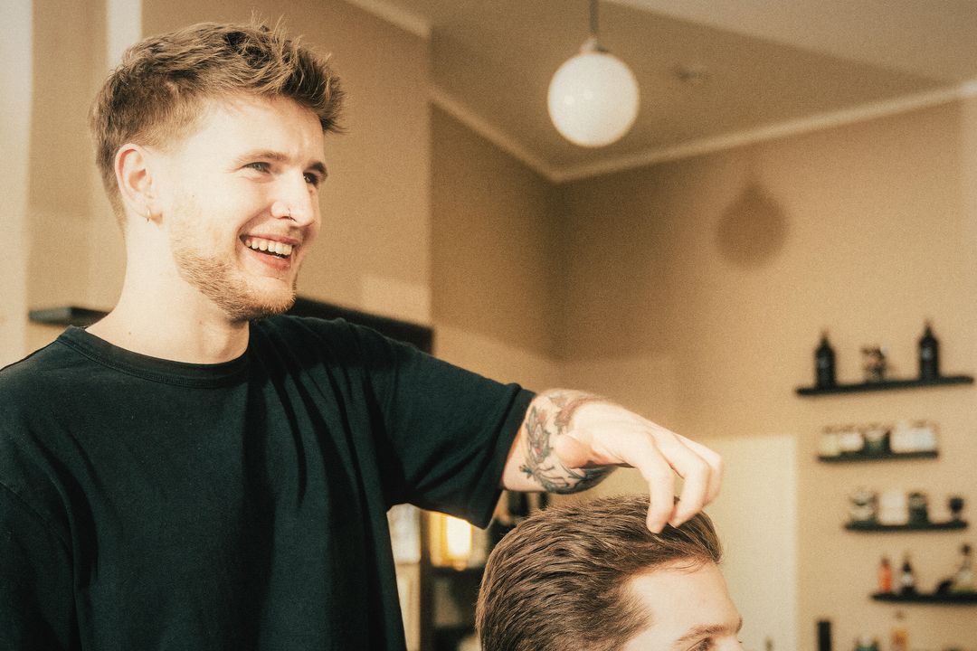 Herrengut barber laughing while styling a customer’s hair